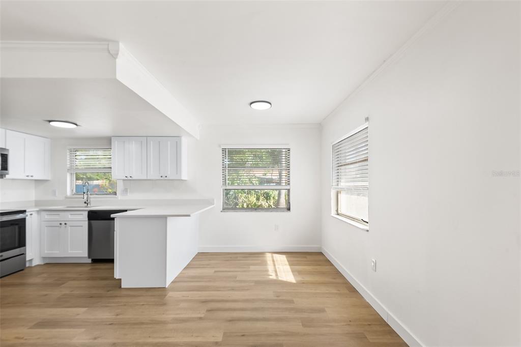A kitchen with white cabinets and a dining area with light wood-look flooring — 555 62ND STREET S UNIT 110, ST PETERSBURG, FL