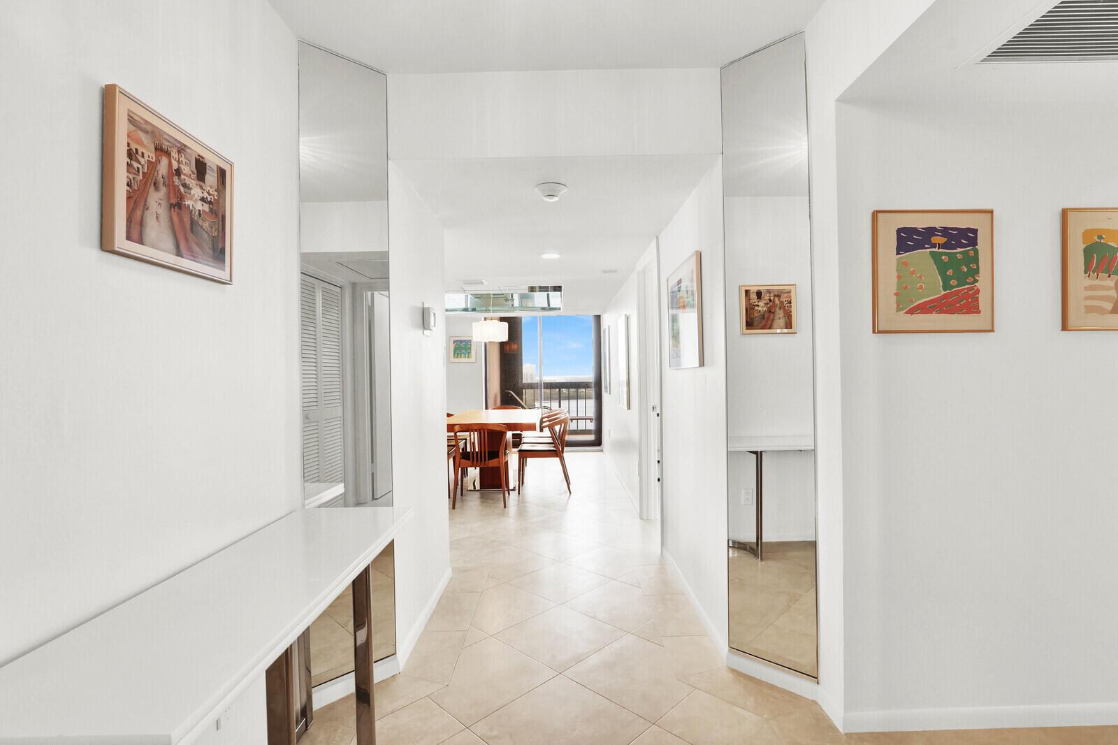 A bright hallway with tiled floors leads to a dining area with a balcony view — 5380 N Ocean Drive # 18a, Singer Island FL 33404, SINGER ISLAND, FL