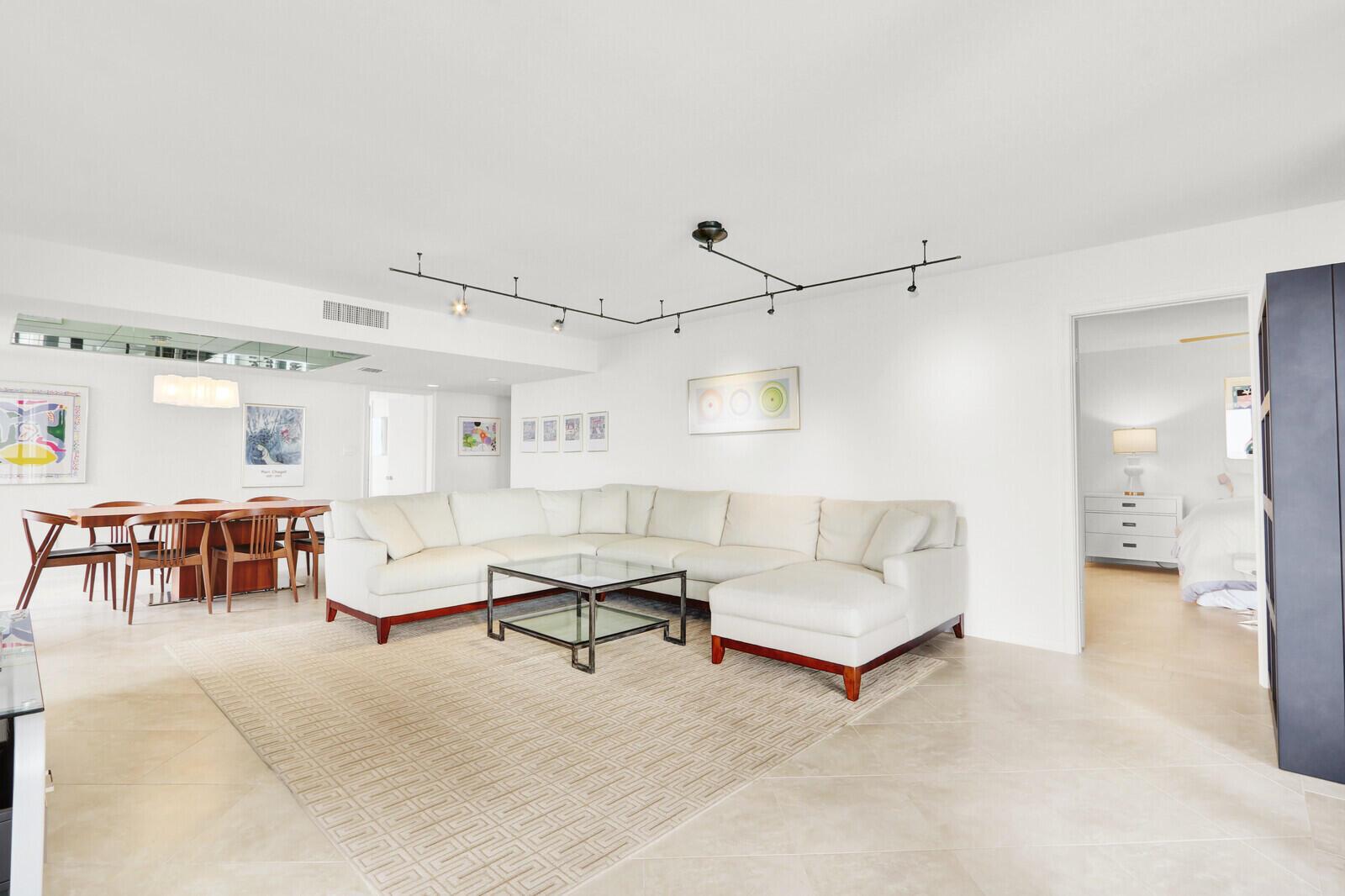 A bright living room features a large white sectional sofa, glass coffee table, and dining area — 5380 N Ocean Drive # 18a, Singer Island FL 33404, SINGER ISLAND, FL