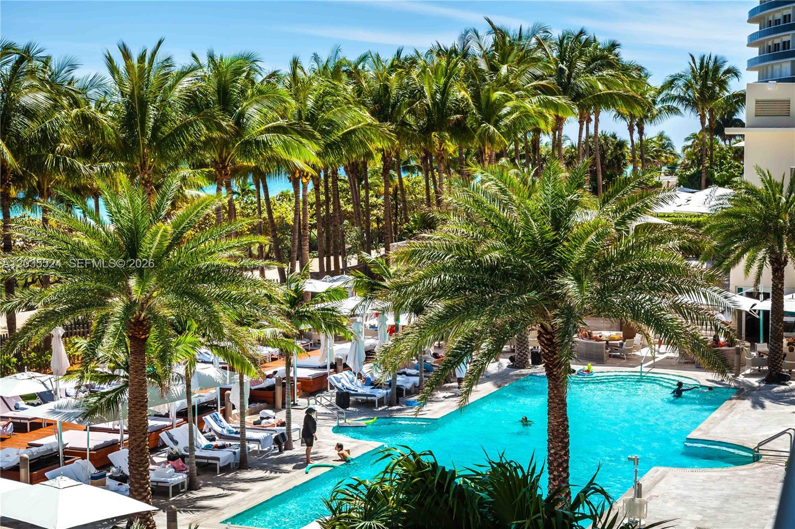 A swimming pool is surrounded by lounge chairs and palm trees at a resort — 9703 Collins Ave, Bal Harbour FL 33154, BAL HARBOUR, FL