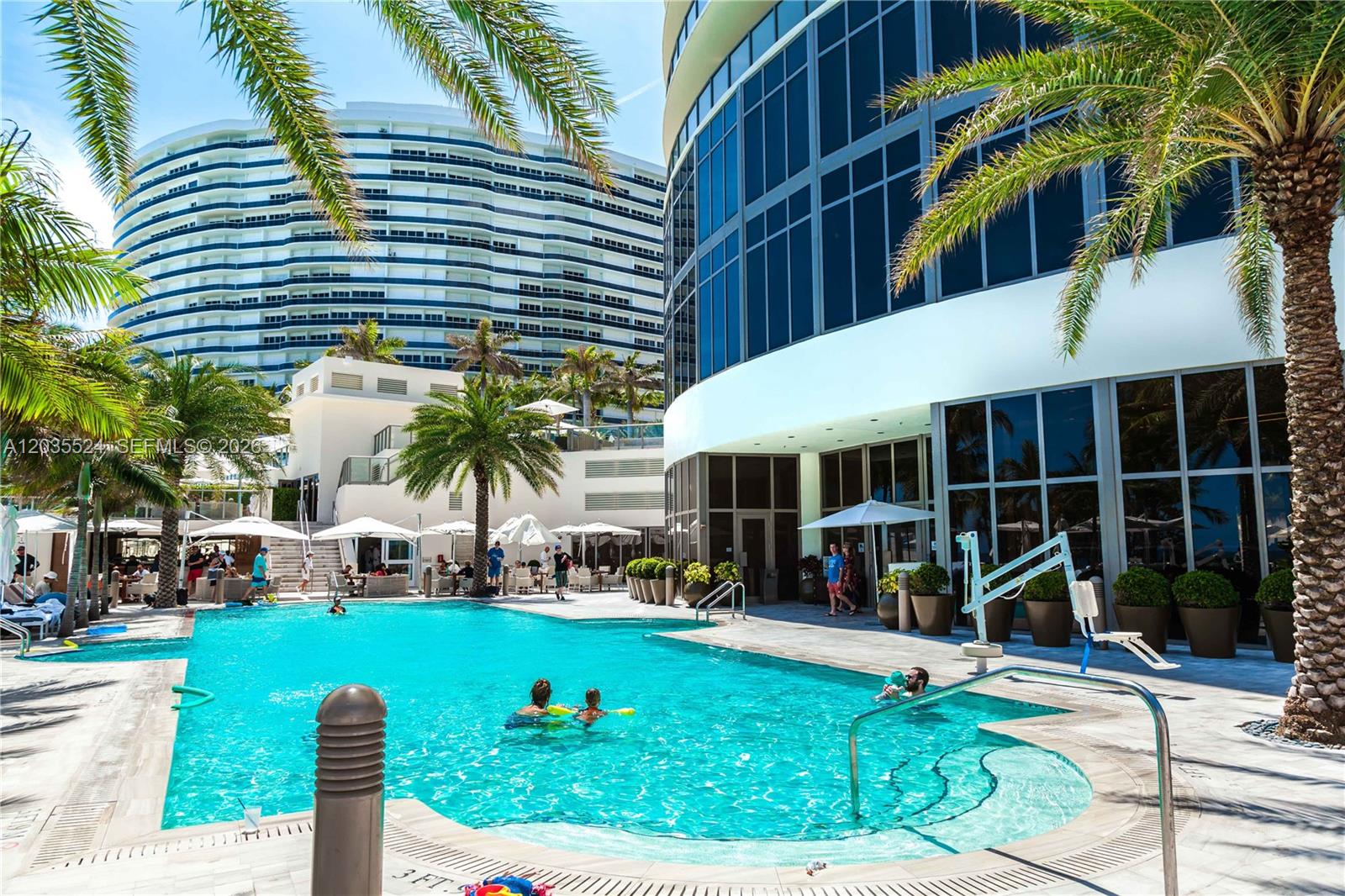 An outdoor swimming pool is surrounded by palm trees and modern high-rise buildings — 9703 Collins Ave, Bal Harbour FL 33154, BAL HARBOUR, FL