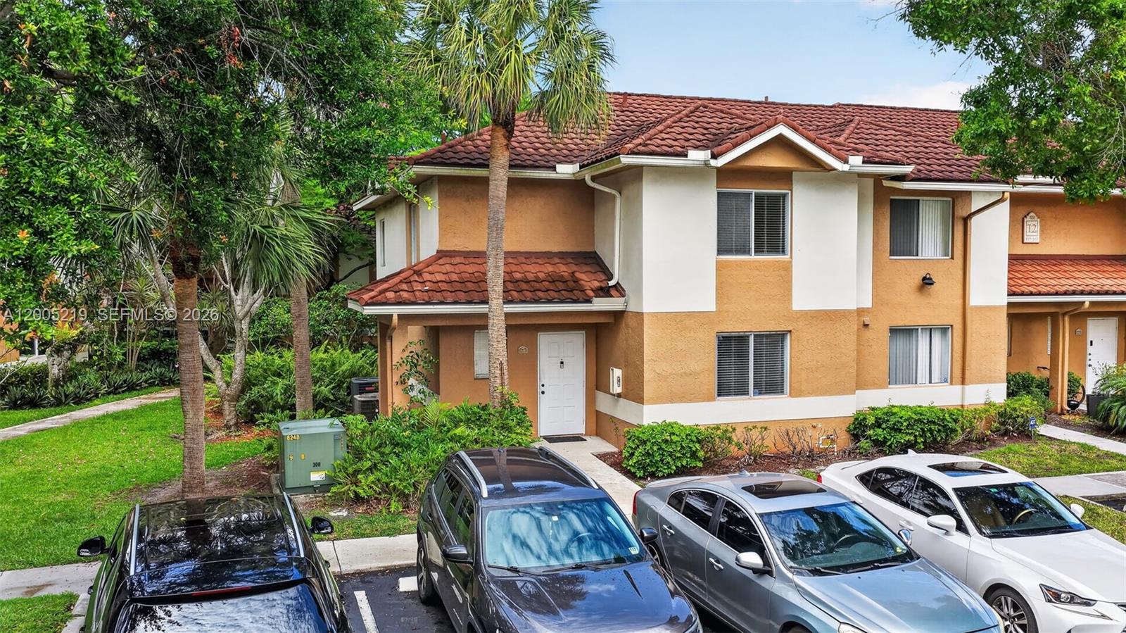 A two-story townhouse with a brown tile roof and tan stucco exterior sits near parking — 845 NW 91st Ter, Plantation FL 33324, PLANTATION, FL