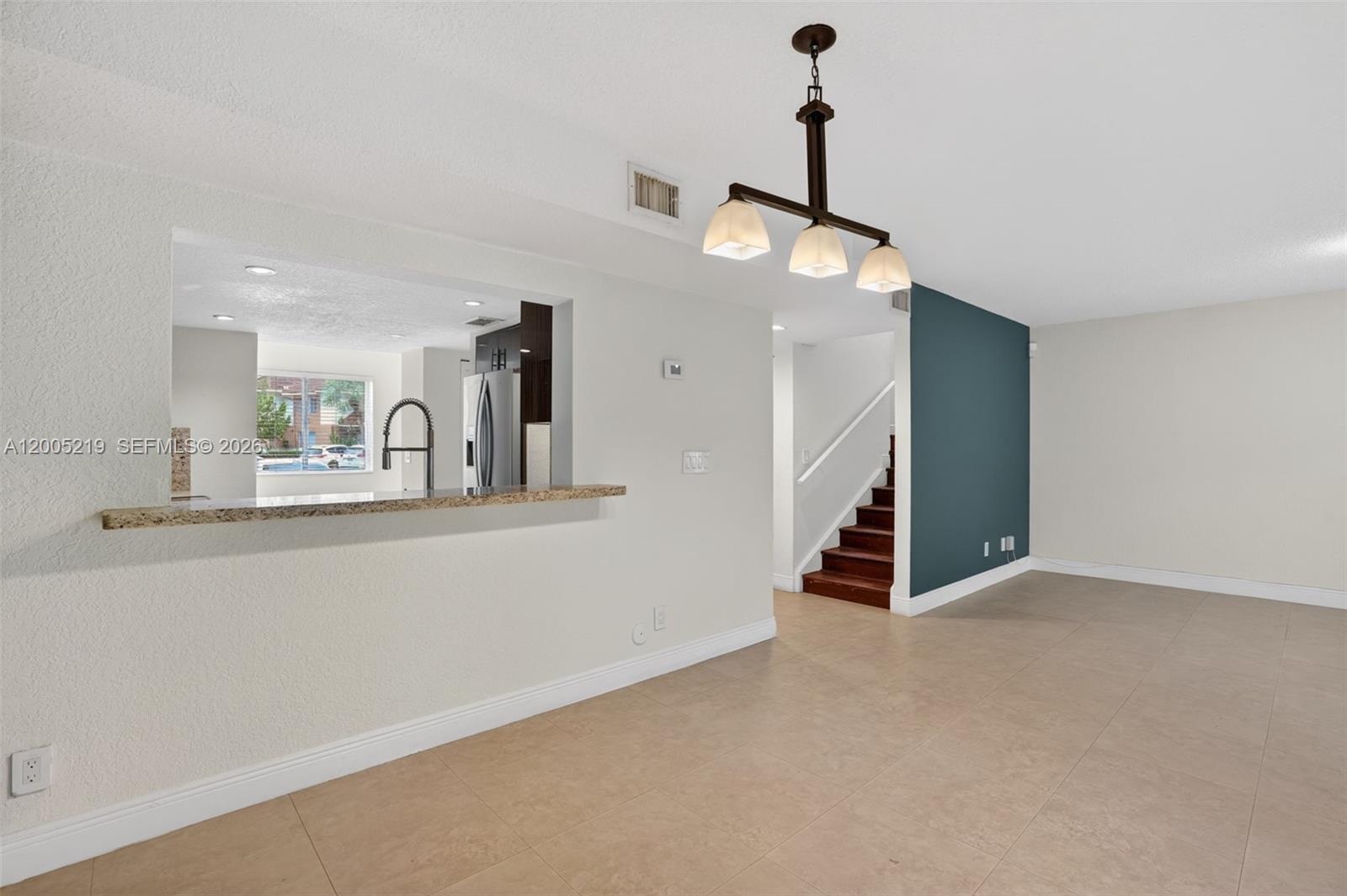 A dining area with tile floors, a breakfast bar, and a staircase with dark wood steps — 845 NW 91st Ter, Plantation FL 33324, PLANTATION, FL