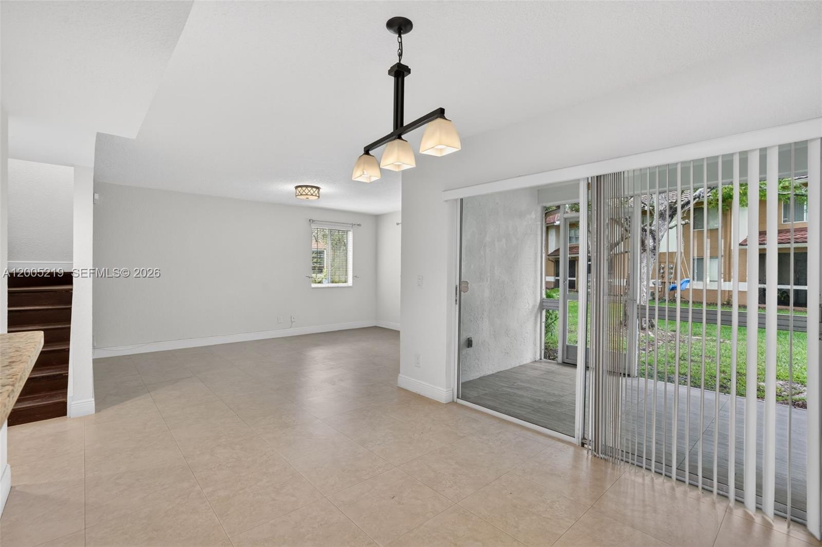 An open living area features tile flooring, a modern chandelier, and sliding glass doors — 845 NW 91st Ter, Plantation FL 33324, PLANTATION, FL
