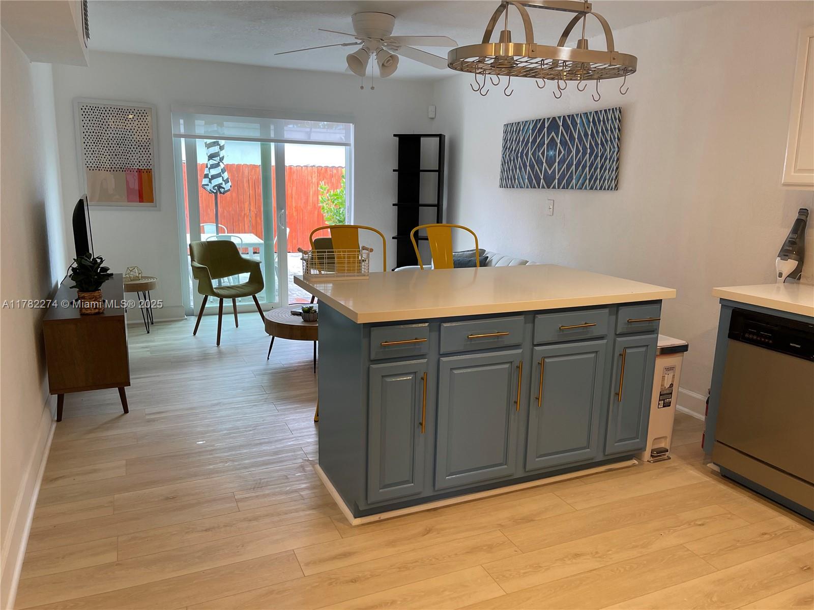 A kitchen island with blue cabinets and a white countertop sits in an open-concept room — 1560 NE 145th St # 2, Miami FL 33161, MIAMI, FL