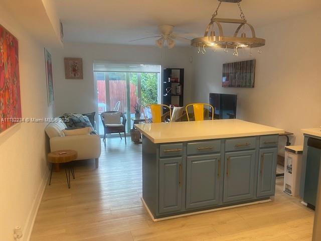 A kitchen island with blue cabinets sits in a living room with light wood flooring — 1560 NE 145th St # 2, Miami FL 33161, MIAMI, FL