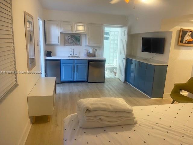 A studio apartment features a kitchenette with blue cabinets, light wood flooring, and a bed — 1560 NE 145th St # 2, Miami FL 33161, MIAMI, FL
