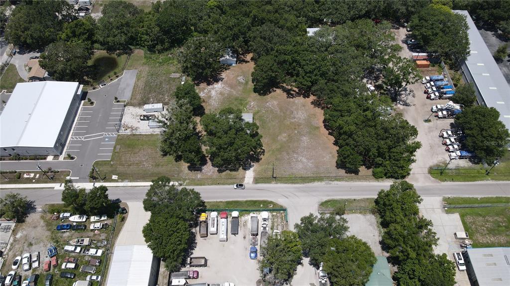An aerial view shows a vacant lot surrounded by trees, adjacent buildings, and parked vehicles — 1406 HOBBS STREET, TAMPA, FL