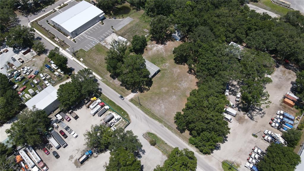 An aerial view shows a commercial property with several buildings, parking areas, and wooded land — 1406 HOBBS STREET, TAMPA, FL