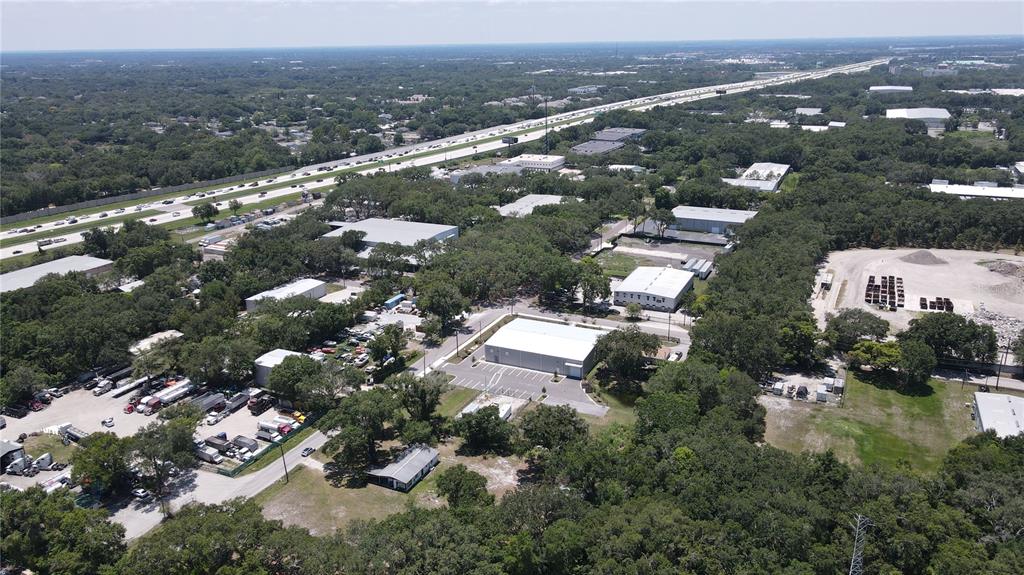 An aerial view shows industrial buildings, a parking lot with trucks, and a nearby highway — 1406 HOBBS STREET, TAMPA, FL
