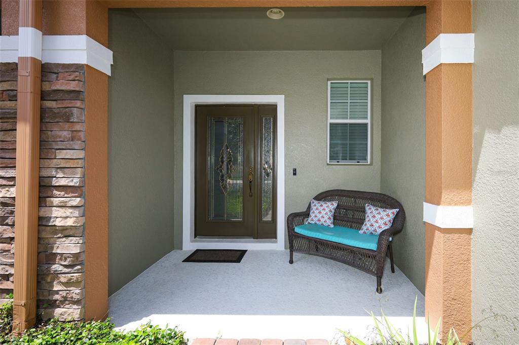 A covered front porch features a brown door with glass panels and a wicker bench — 632 VENICE PLACE, SANFORD, FL
