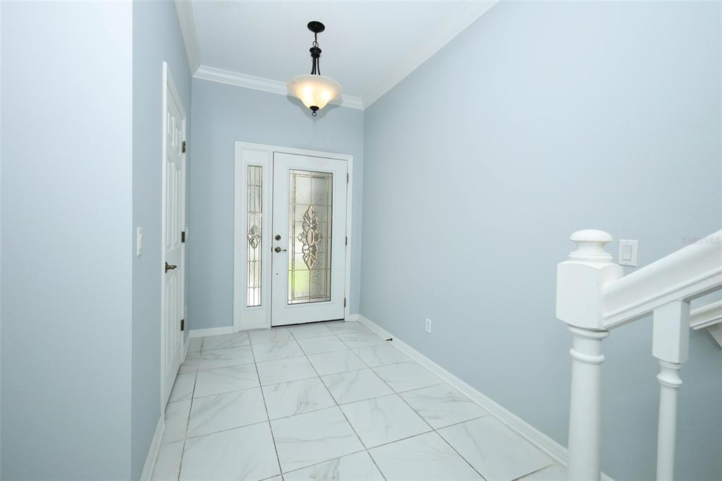 A bright entryway features light blue walls, white tile flooring, and a glass-paneled front door — 632 VENICE PLACE, SANFORD, FL