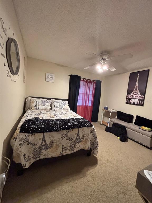 A bedroom features a bed with Eiffel Tower bedding, a ceiling fan, and wall art — 2690 CORAL LANDINGS BOULEVARD UNIT 127, PALM HARBOR, FL