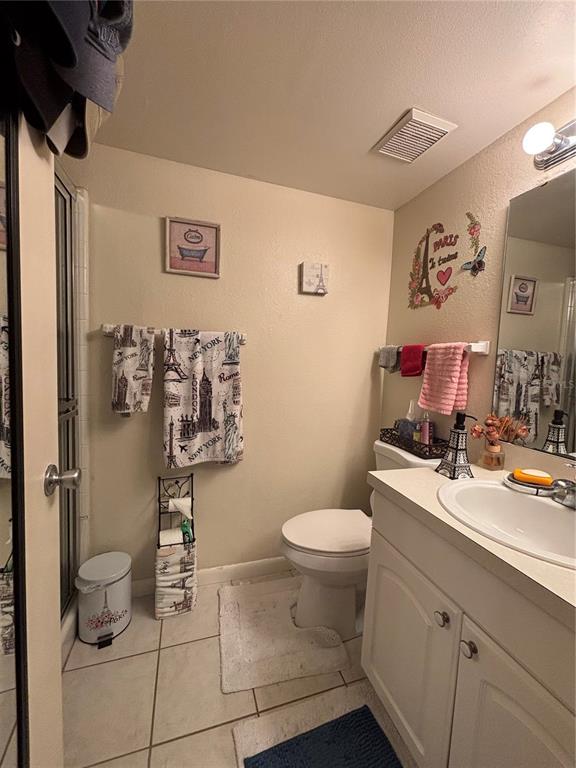 A bathroom features a vanity with a sink, a toilet, and travel-themed wall decor — 2690 CORAL LANDINGS BOULEVARD UNIT 127, PALM HARBOR, FL
