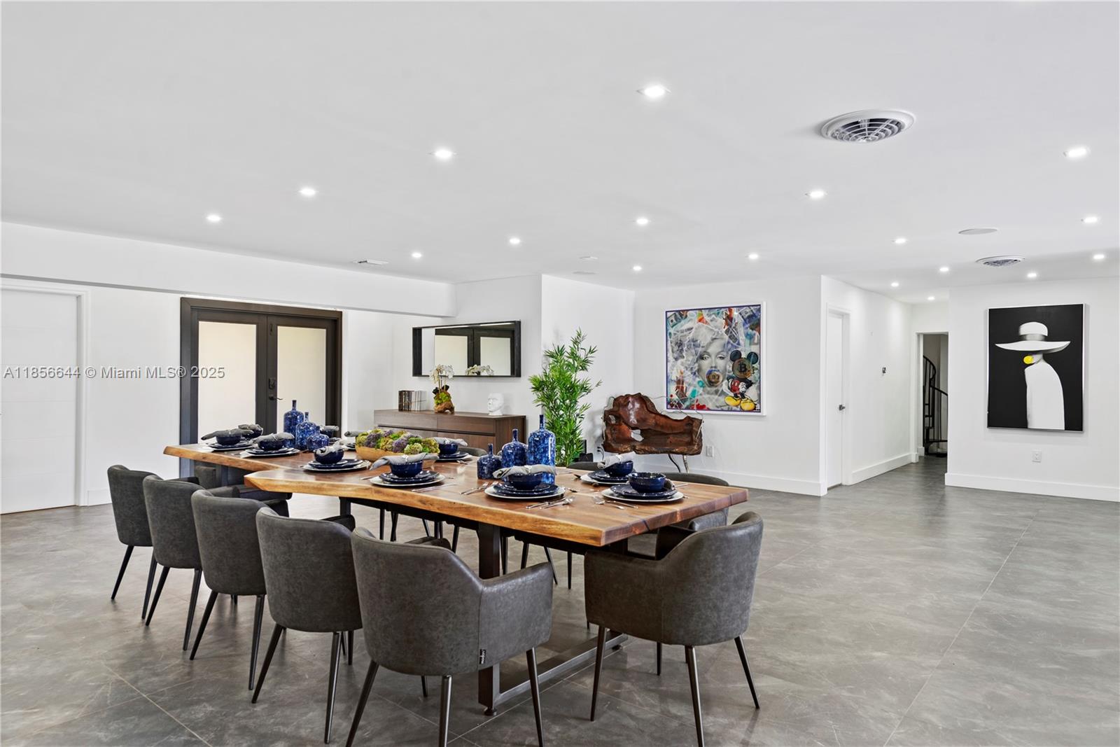 A dining room features a large wooden table, grey chairs, and modern art on white walls — 4322 Polk St, Hollywood FL 33021, HOLLYWOOD, FL