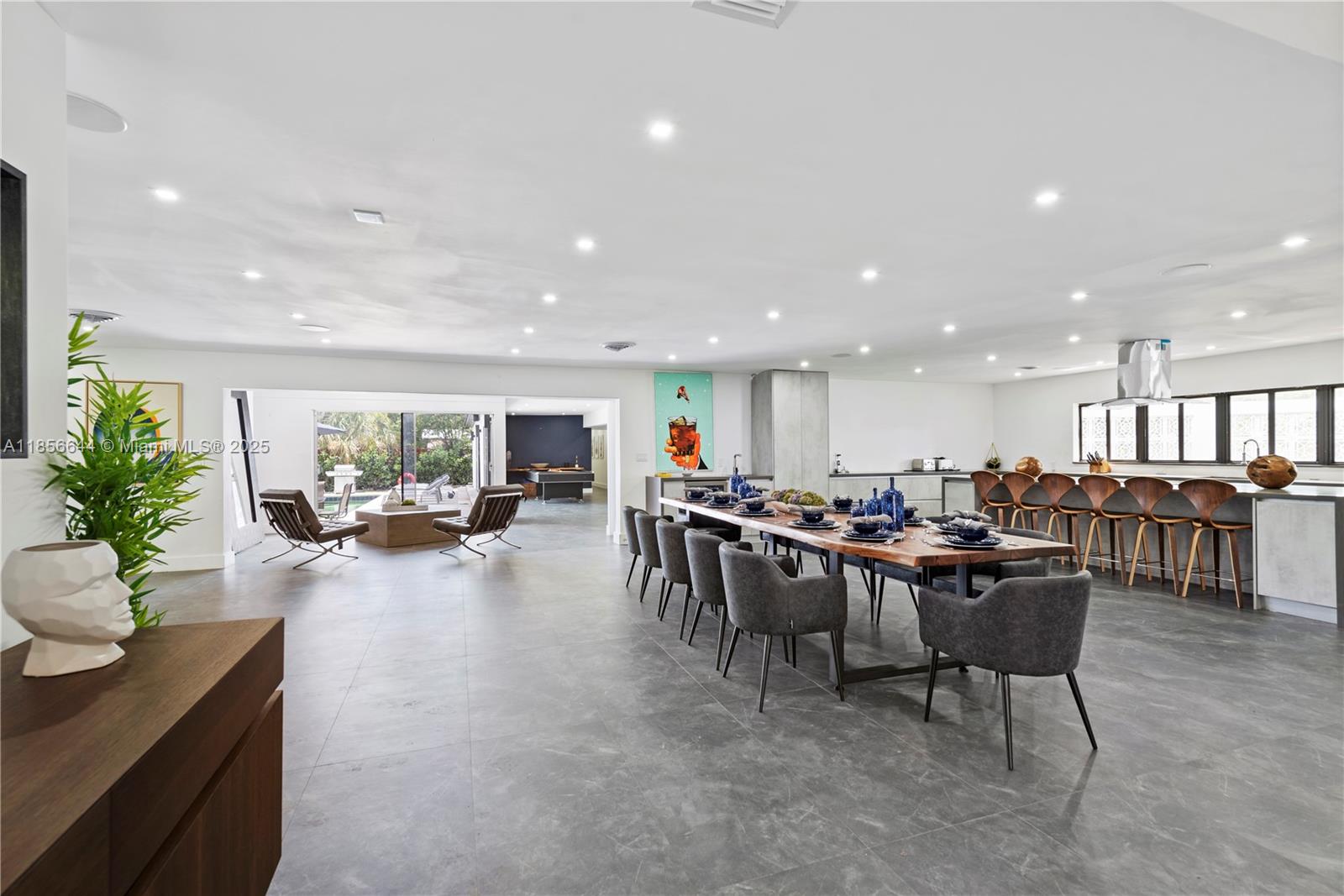 A spacious open-concept dining and kitchen area features a long wooden table and tile flooring — 4322 Polk St, Hollywood FL 33021, HOLLYWOOD, FL