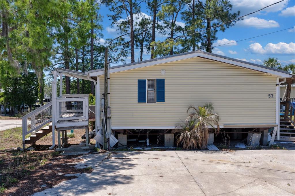 A light yellow mobile home with blue shutters sits on a concrete driveway — 53 SE 241ST STREET, SUWANNEE, FL