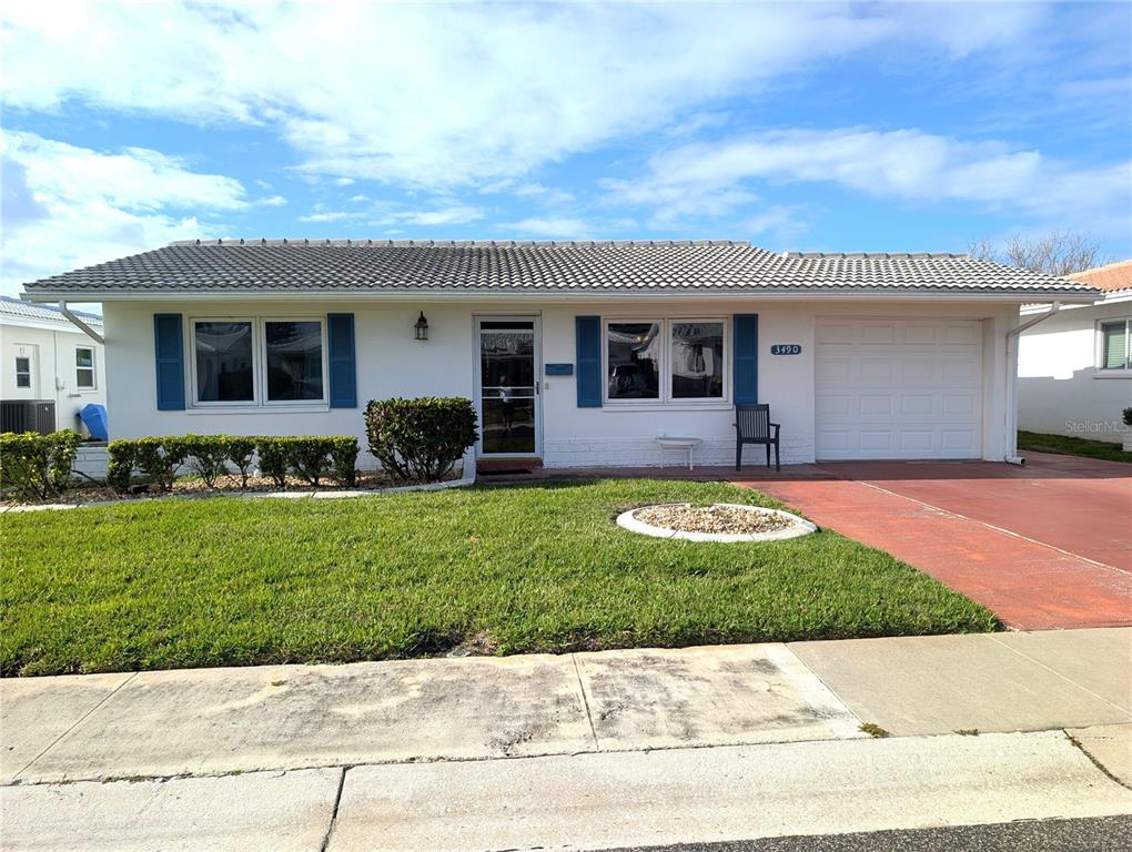 A single-story white house with blue shutters, a tile roof, and an attached garage — 3490 101ST TERRACE N, PINELLAS PARK, FL