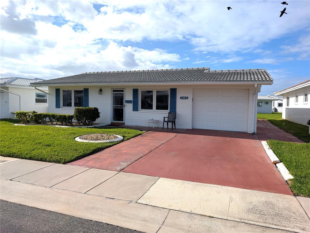 A single-story house with a white exterior, blue shutters, and a red concrete driveway — 3490 101ST TERRACE N, PINELLAS PARK, FL