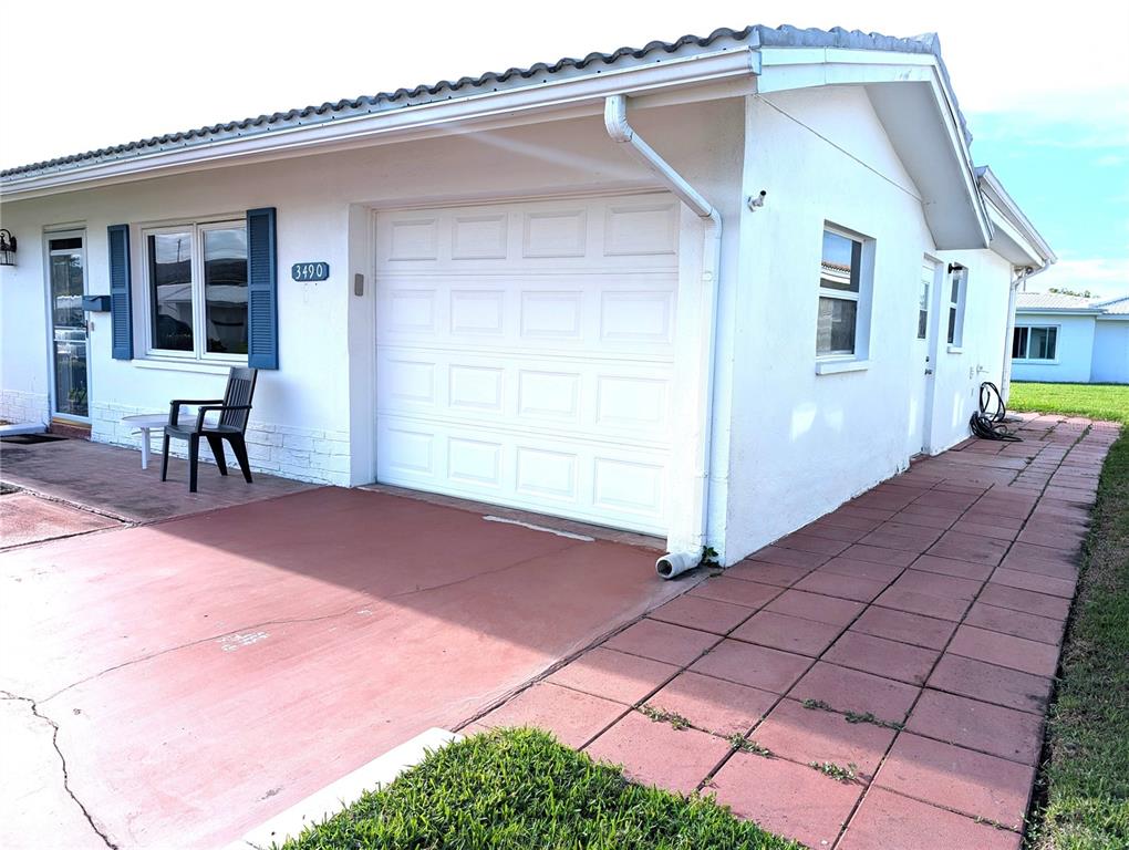A white house exterior features a garage, a side walkway, and a small patio area — 3490 101ST TERRACE N, PINELLAS PARK, FL