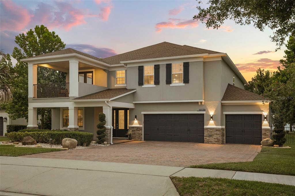 A two-story suburban house features a paved driveway, a three-car garage, and an upper balcony — 16038 JOHNS LAKE OVERLOOK DRIVE, WINTER GARDEN, FL