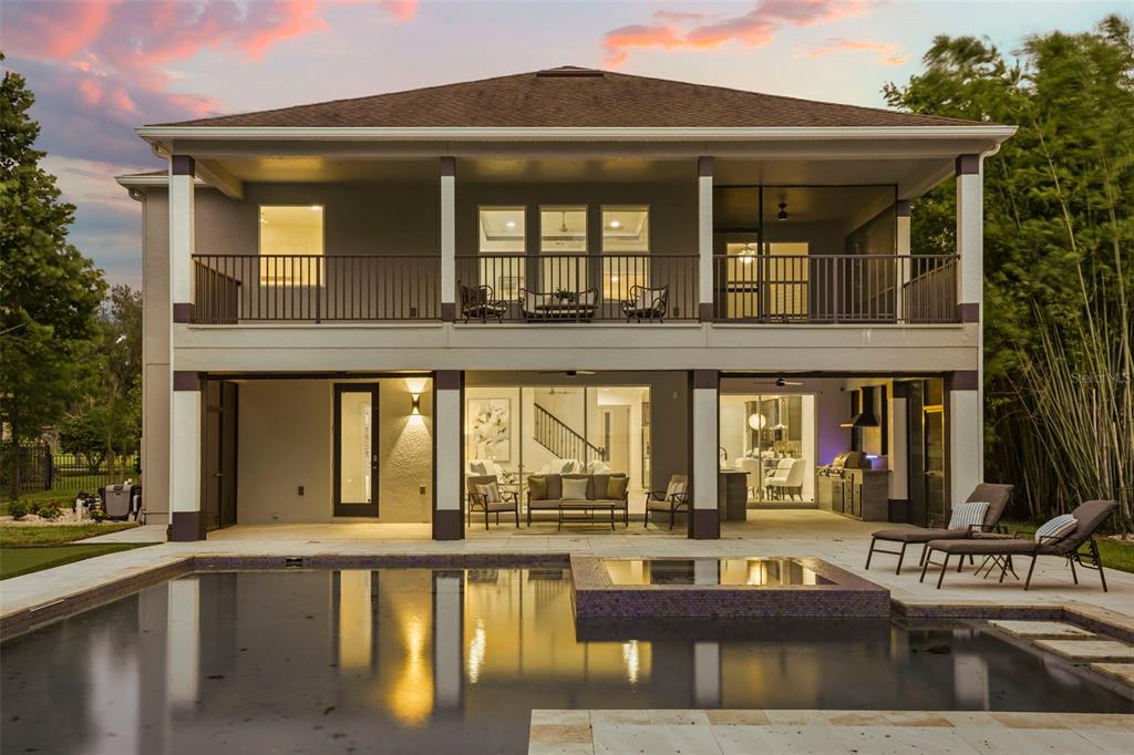 The rear exterior of a two-story house features a swimming pool, patio, and upper balcony — 16038 JOHNS LAKE OVERLOOK DRIVE, WINTER GARDEN, FL
