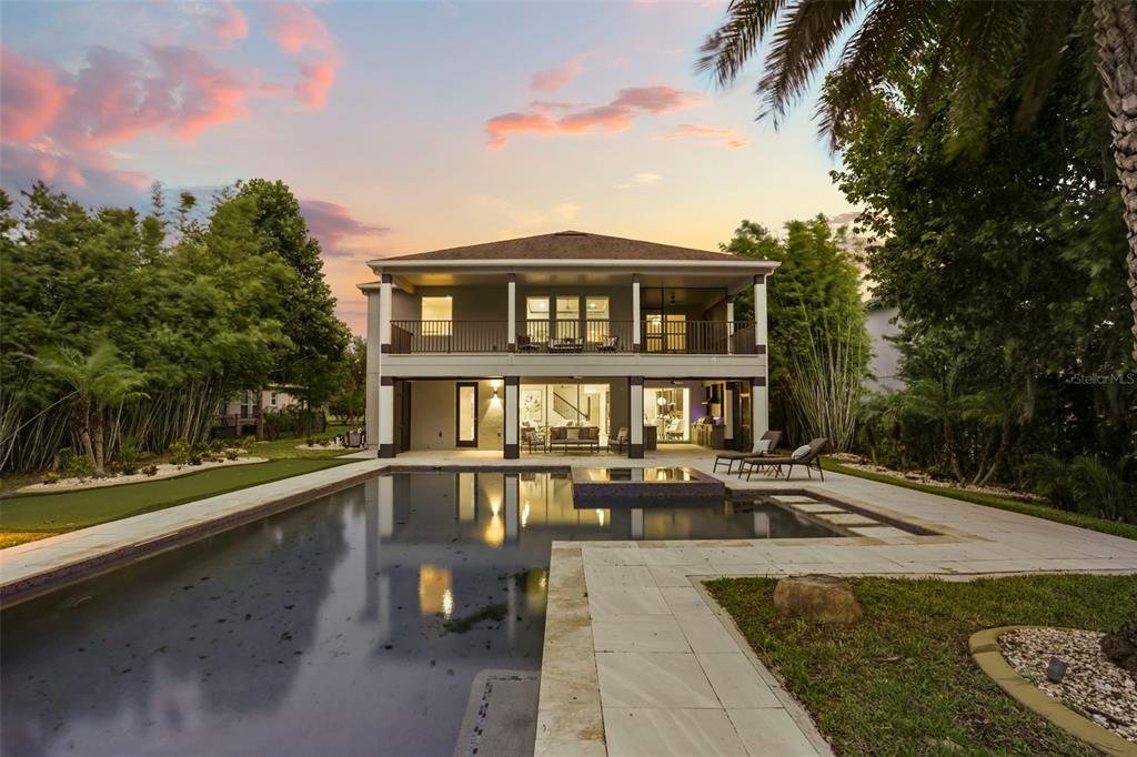 A two-story house exterior features a swimming pool, a covered patio, and a second-floor balcony — 16038 JOHNS LAKE OVERLOOK DRIVE, WINTER GARDEN, FL