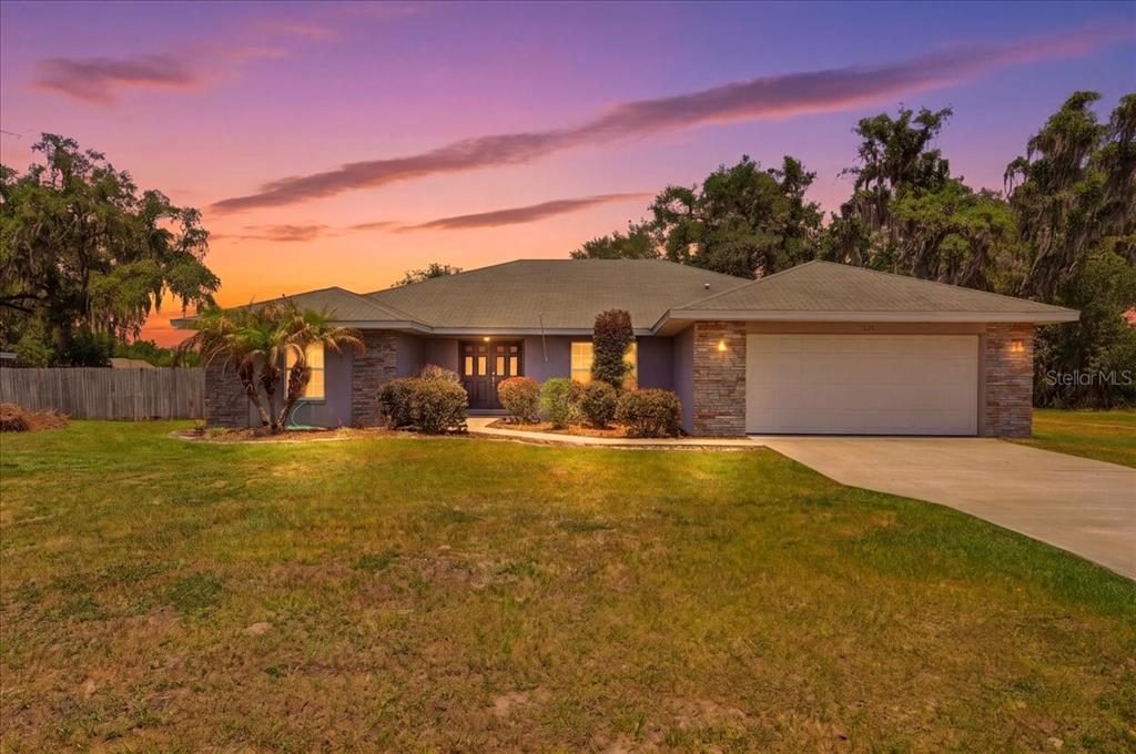 A single-story house with a stone facade, a two-car garage, and a lawn at sunset — 1233 PARKER ROAD, LAKELAND, FL
