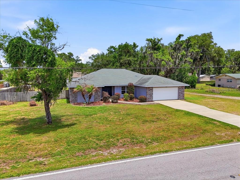 A single-story house with a stone facade, a green roof, and a two-car garage — 1233 PARKER ROAD, LAKELAND, FL