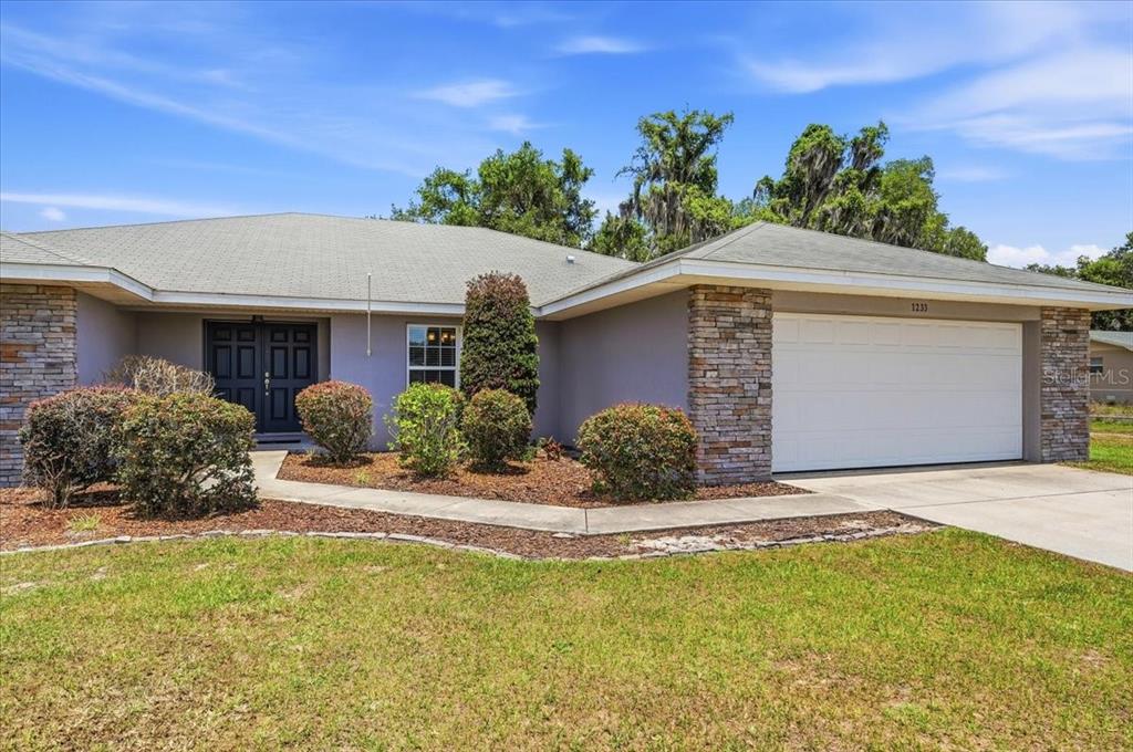 A single-story house with a stone-accented facade, a two-car garage, and a landscaped front yard — 1233 PARKER ROAD, LAKELAND, FL