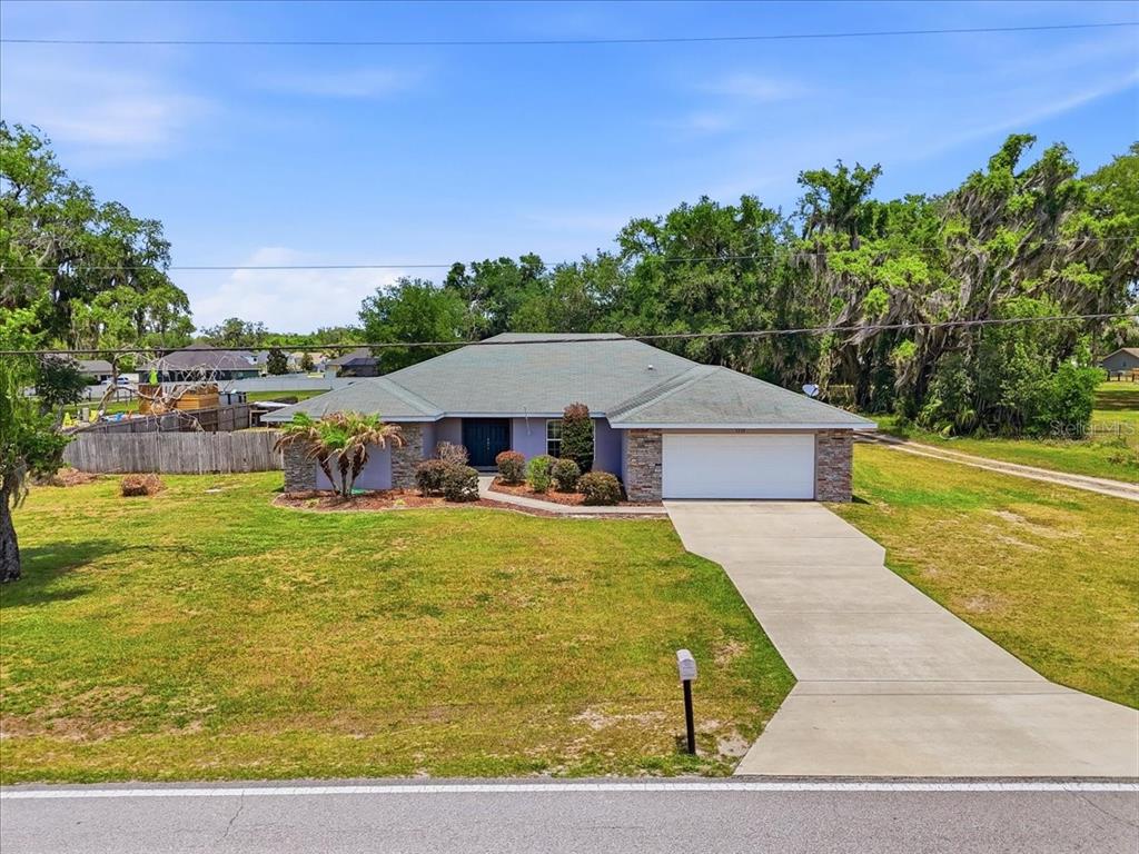A single-story house with a stone facade, a two-car garage, and a large front lawn — 1233 PARKER ROAD, LAKELAND, FL