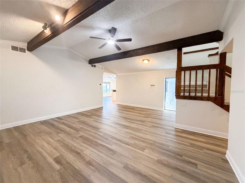 A living room with wood-look flooring, exposed ceiling beams, a ceiling fan, and a staircase — 37 OSPREY STREET, SAFETY HARBOR, FL