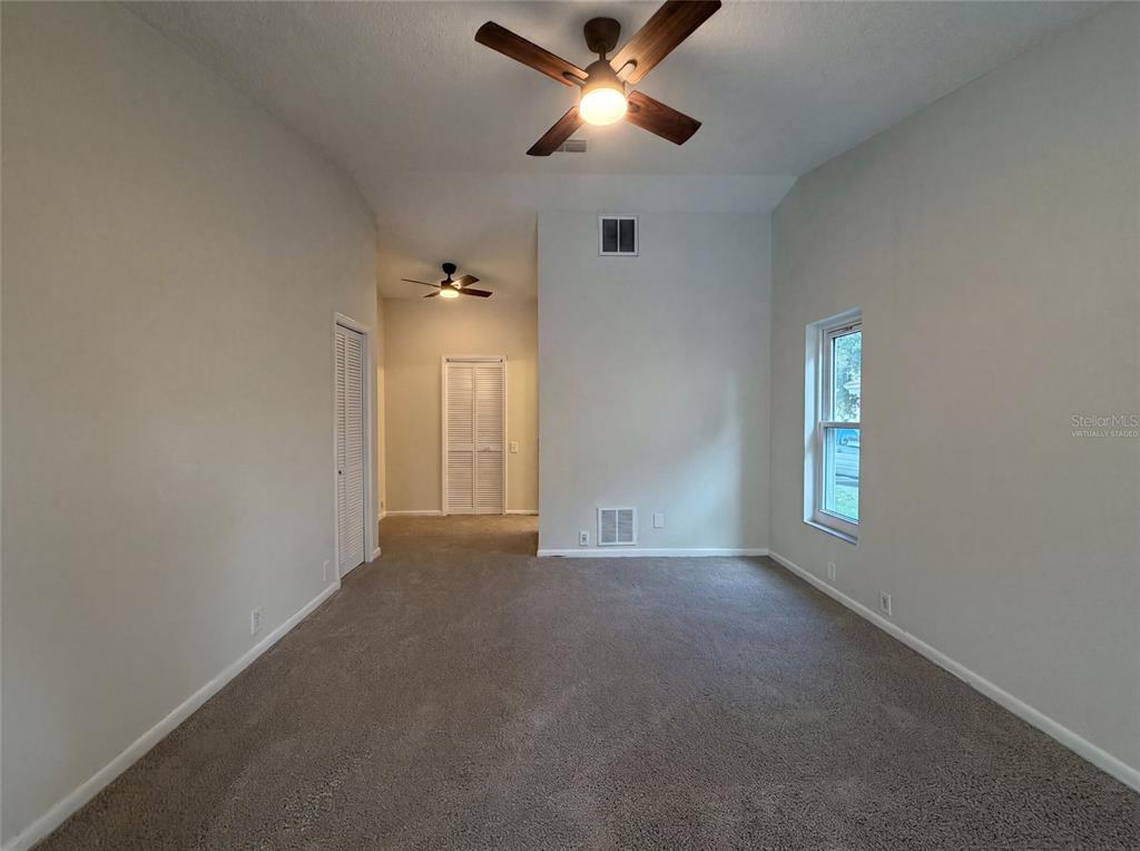 An empty room with carpeted floors, two ceiling fans, and a window on the right — 37 OSPREY STREET, SAFETY HARBOR, FL