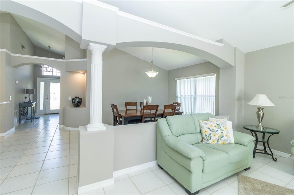 A living room with a light green sofa and a dining area behind a half-wall — 1057 SOARING EAGLE LANE, KISSIMMEE, FL