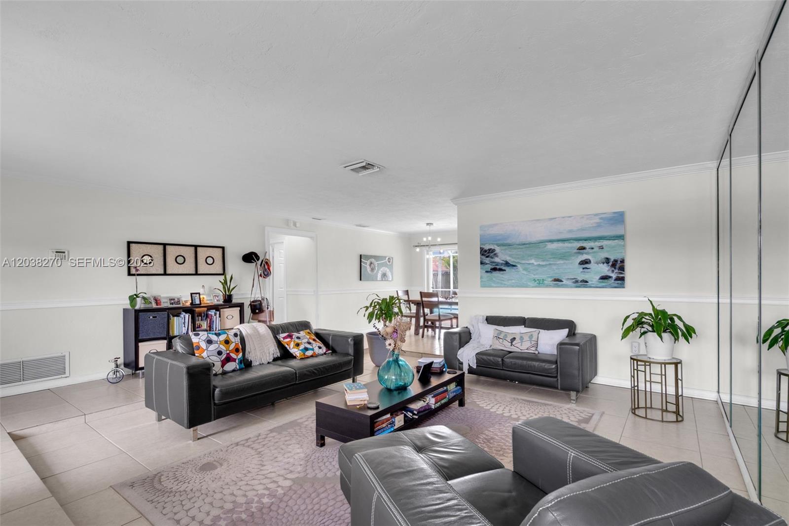 A living room features gray leather sofas, a coffee table, and a large ocean painting — 9624 NW 19th Pl, Sunrise FL 33322, SUNRISE, FL