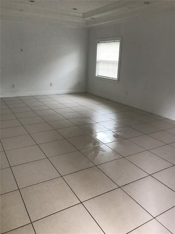 A spacious, empty room features light-colored floor tiles, white walls, and a recessed ceiling — 1911 MAY STREET, BRANDON, FL