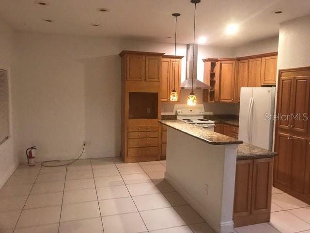 A kitchen features wood cabinets, a granite-topped peninsula, stainless steel appliances, and tile flooring — 1911 MAY STREET, BRANDON, FL