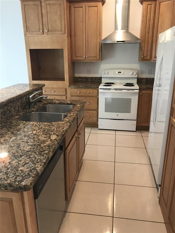 A kitchen features light wood cabinets, granite countertops, a white stove, and tile flooring — 1911 MAY STREET, BRANDON, FL