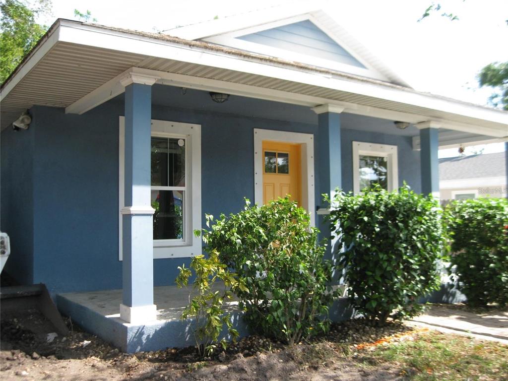 A blue house with a covered front porch, white trim, and a yellow front door — 1057 32ND STREET, SARASOTA, FL
