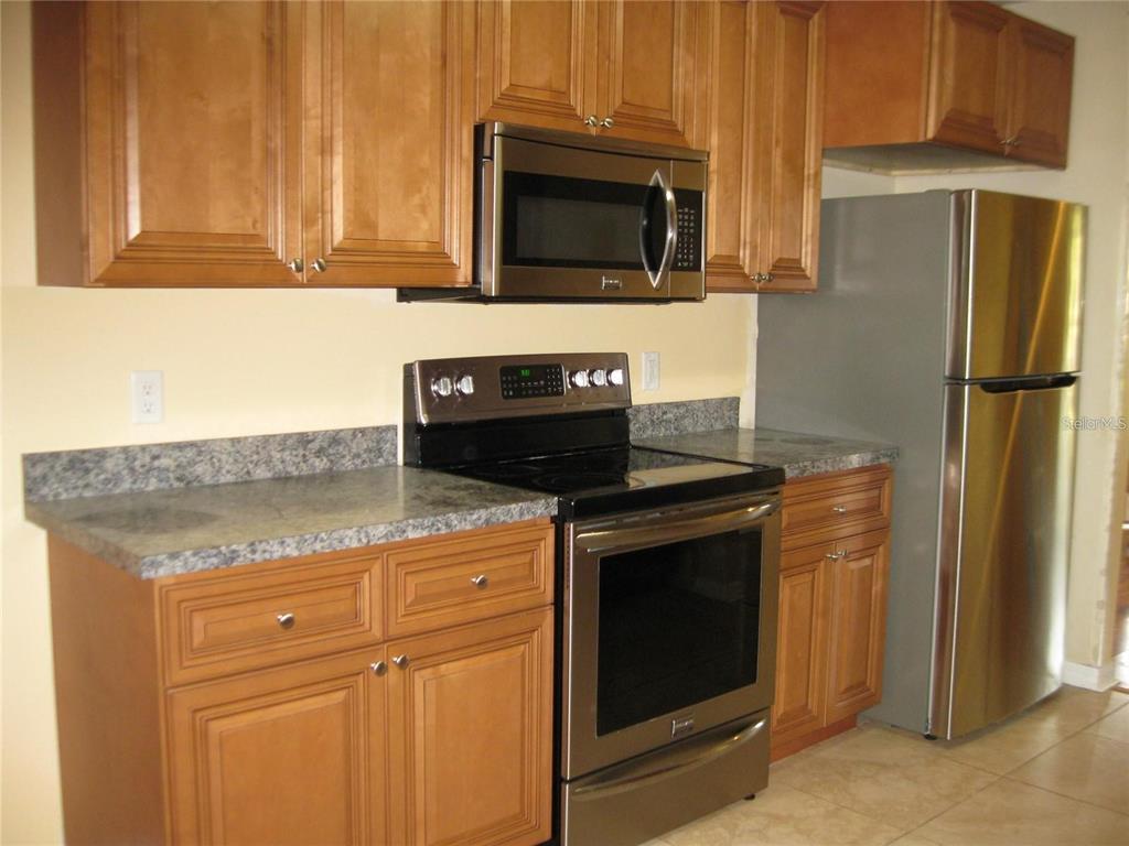 A kitchen features wood cabinets, stainless steel appliances, and gray laminate countertops — 1057 32ND STREET, SARASOTA, FL