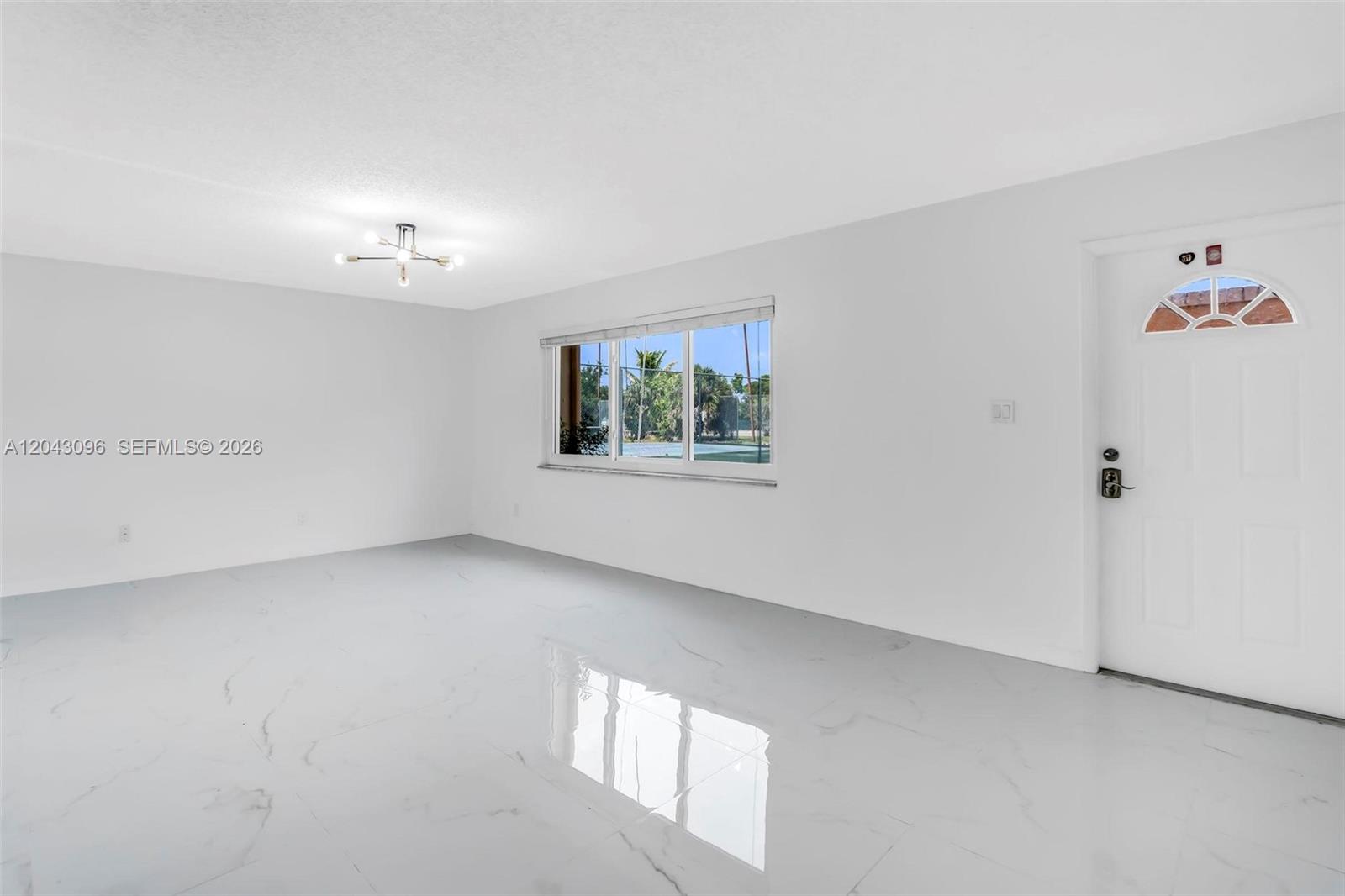 A bright, empty room features white walls, glossy tile flooring, and a single window — 22 Canterbury Ln # 22, Tamarac FL 33319, TAMARAC, FL