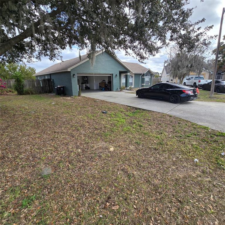 A teal single-story house with a two-car garage and a driveway featuring a black car — 108 CHRIS COURT, DAVENPORT, FL