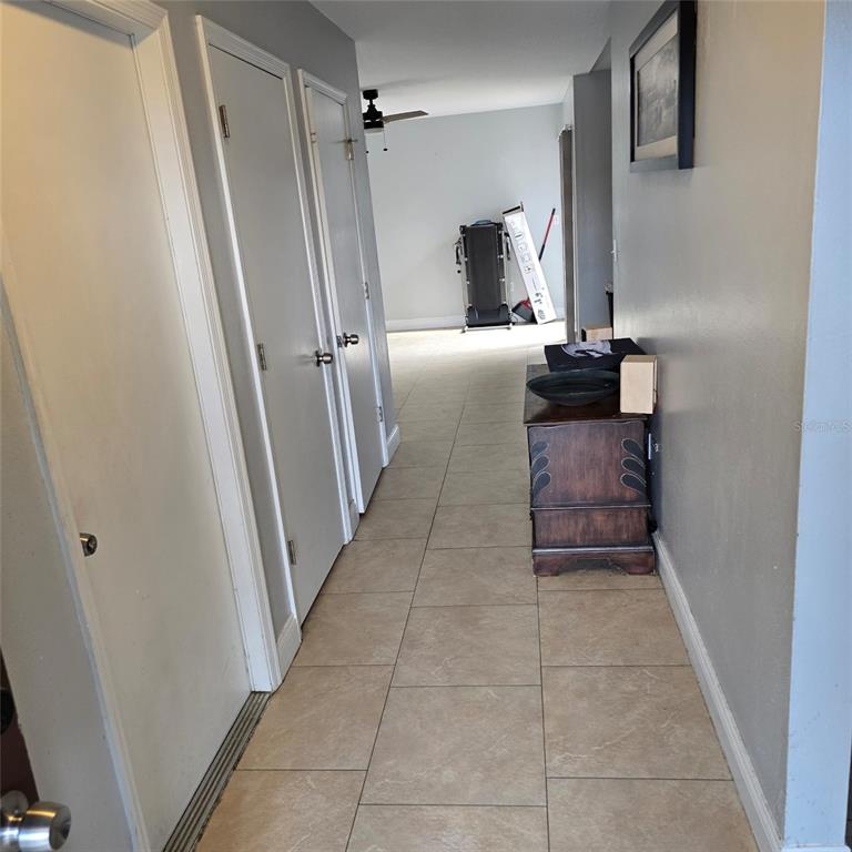 A hallway with tiled floors leads toward a room containing a treadmill and ceiling fan — 108 CHRIS COURT, DAVENPORT, FL