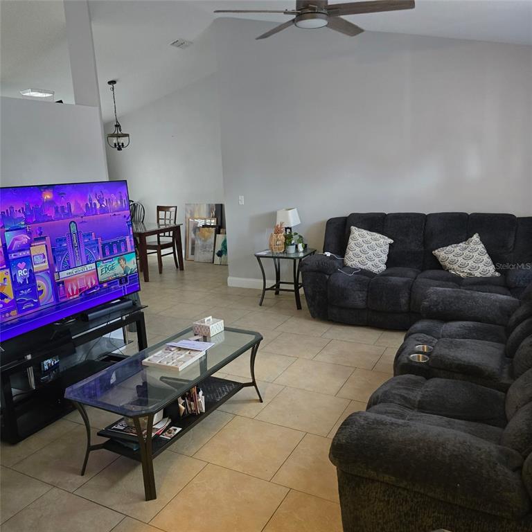 A living room features tile flooring, a dark sectional sofa, and a television on a stand — 108 CHRIS COURT, DAVENPORT, FL
