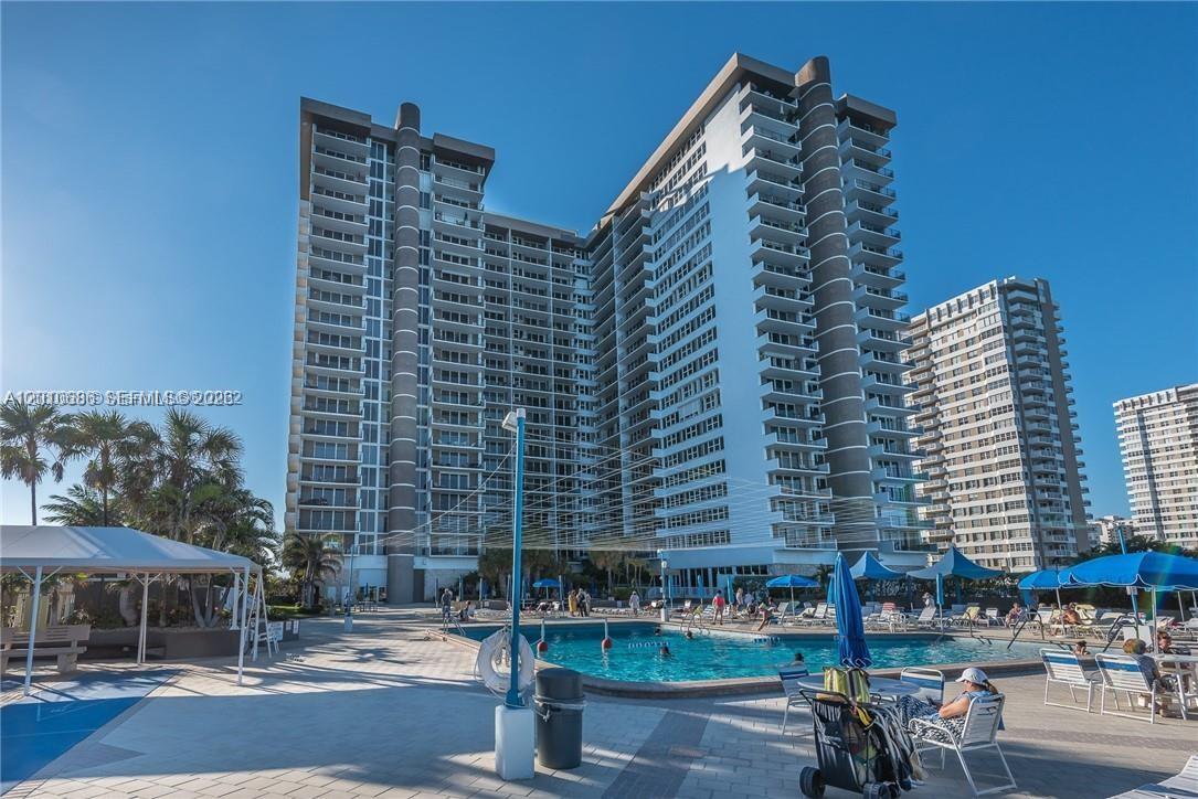 A swimming pool sits on a patio in front of a large residential high-rise building — 2030 S Ocean Dr # 1706, Hallandale Beach FL 33009, HALLANDALE BEACH, FL