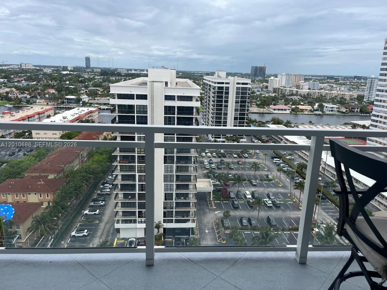 A high-angle view from a balcony overlooking a parking lot, residential buildings, and a waterway — 2030 S Ocean Dr # 1706, Hallandale Beach FL 33009, HALLANDALE BEACH, FL