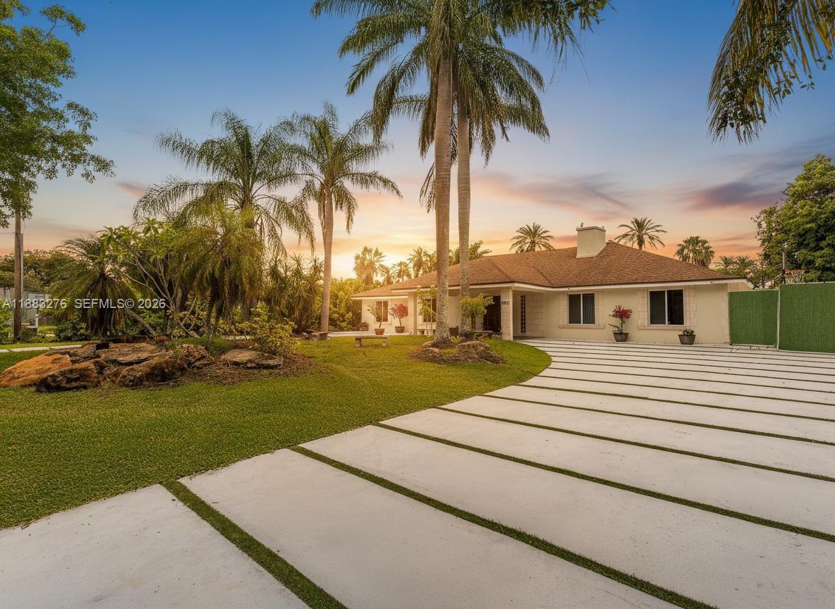 A single-story house with a concrete driveway and palm trees under a sunset sky — 14401 SW 23rd St, Davie FL 33325, DAVIE, FL