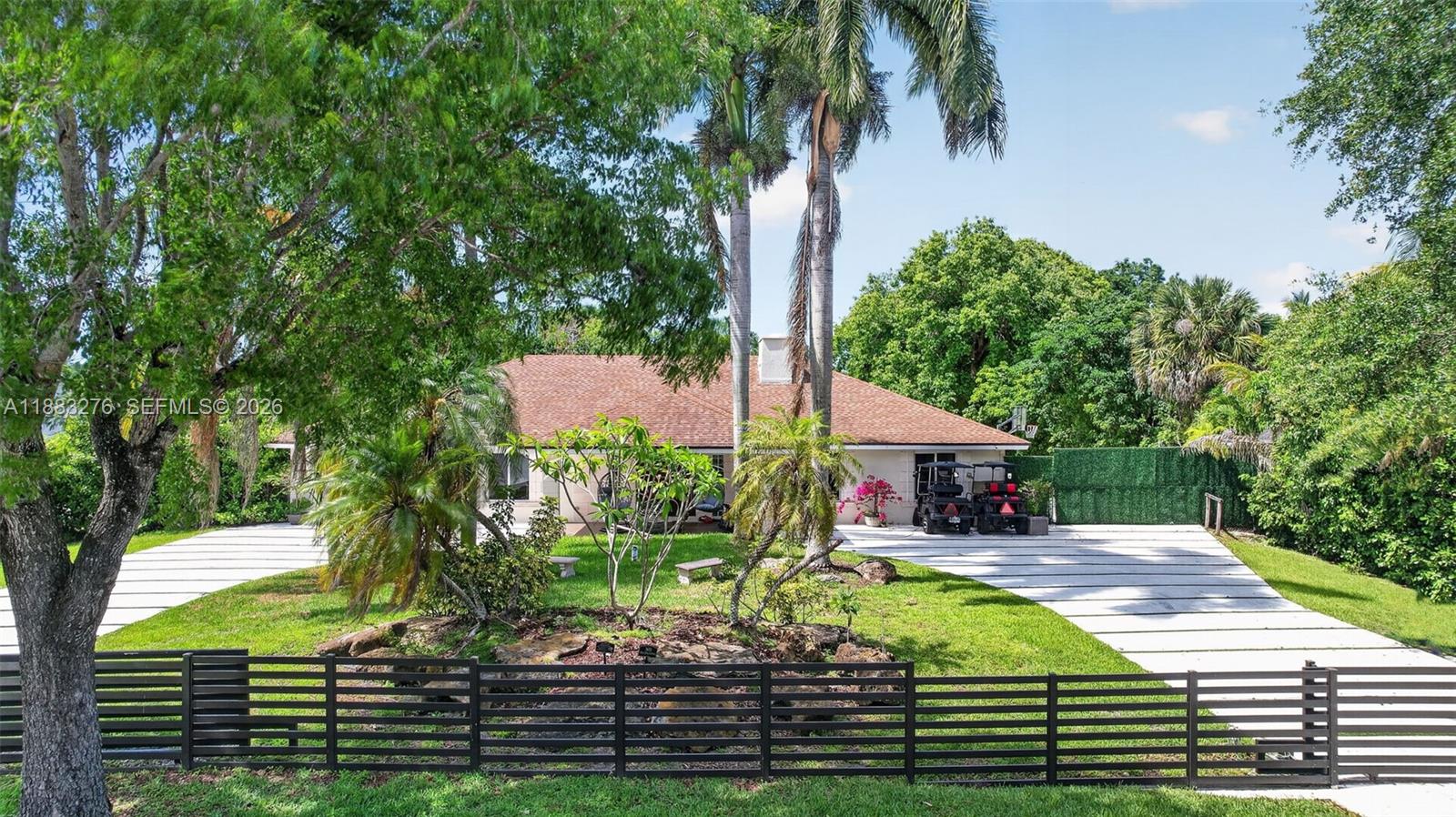 A single-story house with a shingled roof sits behind a black horizontal slat fence — 14401 SW 23rd St, Davie FL 33325, DAVIE, FL