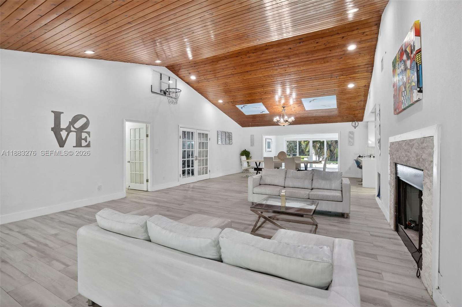 A spacious living room features a vaulted wood-paneled ceiling, white walls, and a stone fireplace — 14401 SW 23rd St, Davie FL 33325, DAVIE, FL