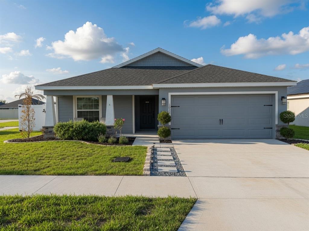 A single-story gray house with a two-car garage and a front walkway with pavers — 1032 ZION DRIVE, HAINES CITY, FL